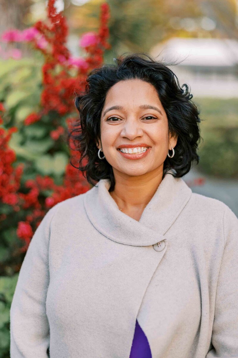 Woman wearing a cream sweater blouse and smiling at the camera.