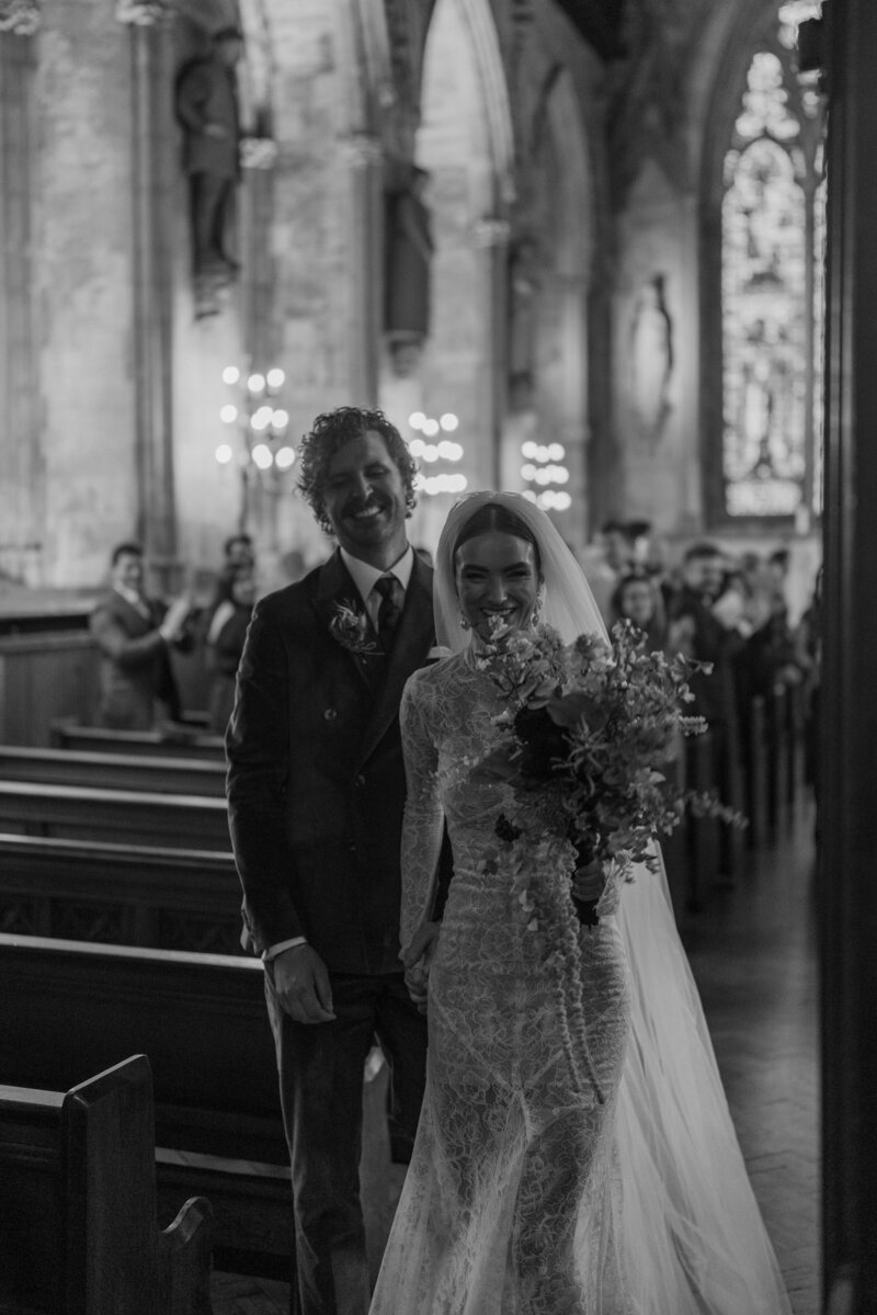 bride points her styled bouquet to the wedding photographers camera inside their intimate ceremony at st etheldreda's church central london