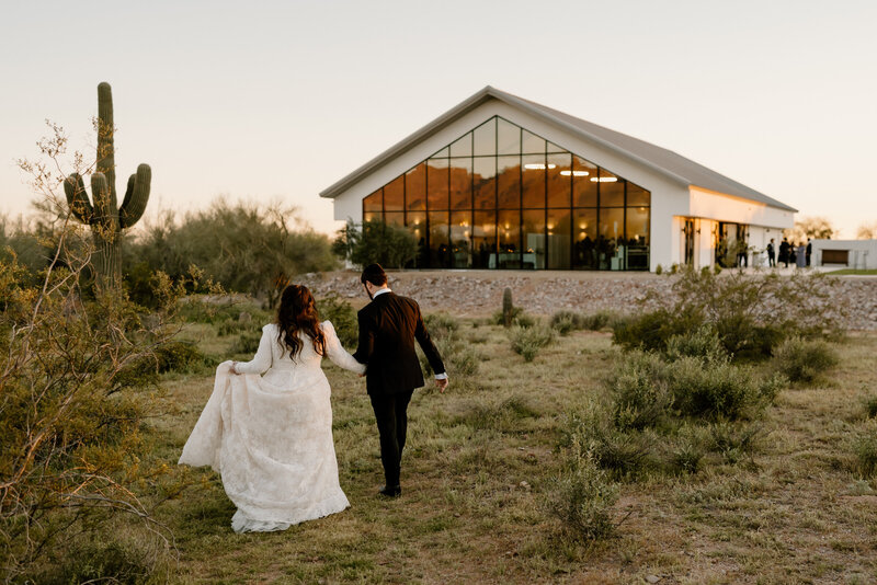 newlyweds walk in arizona landscape to venue