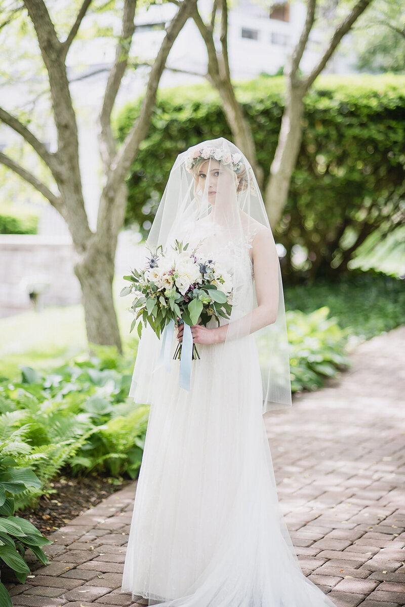 Bride walking solo in a garden, soft light and veil blowing gently—symbolizing the sacred, unforced moments of the day.