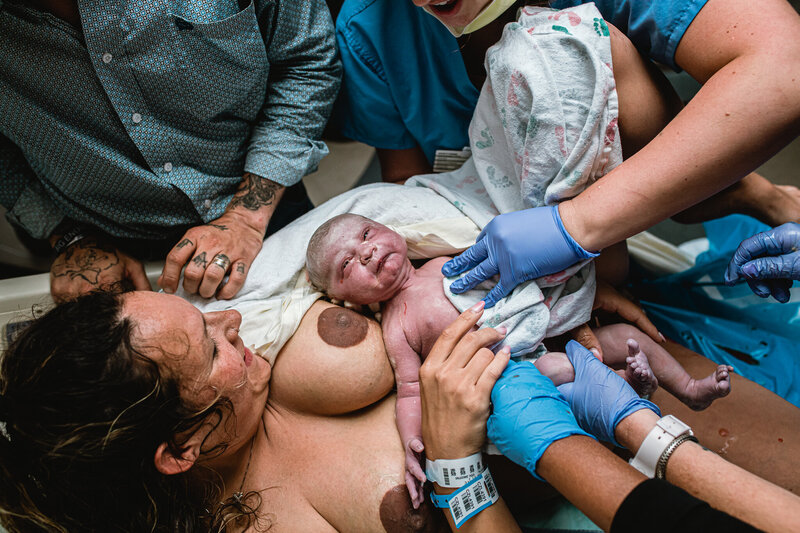 Mother delivering baby during hospital birth with support team present — raw emotional moment captured by Fort Worth birth photographer.
