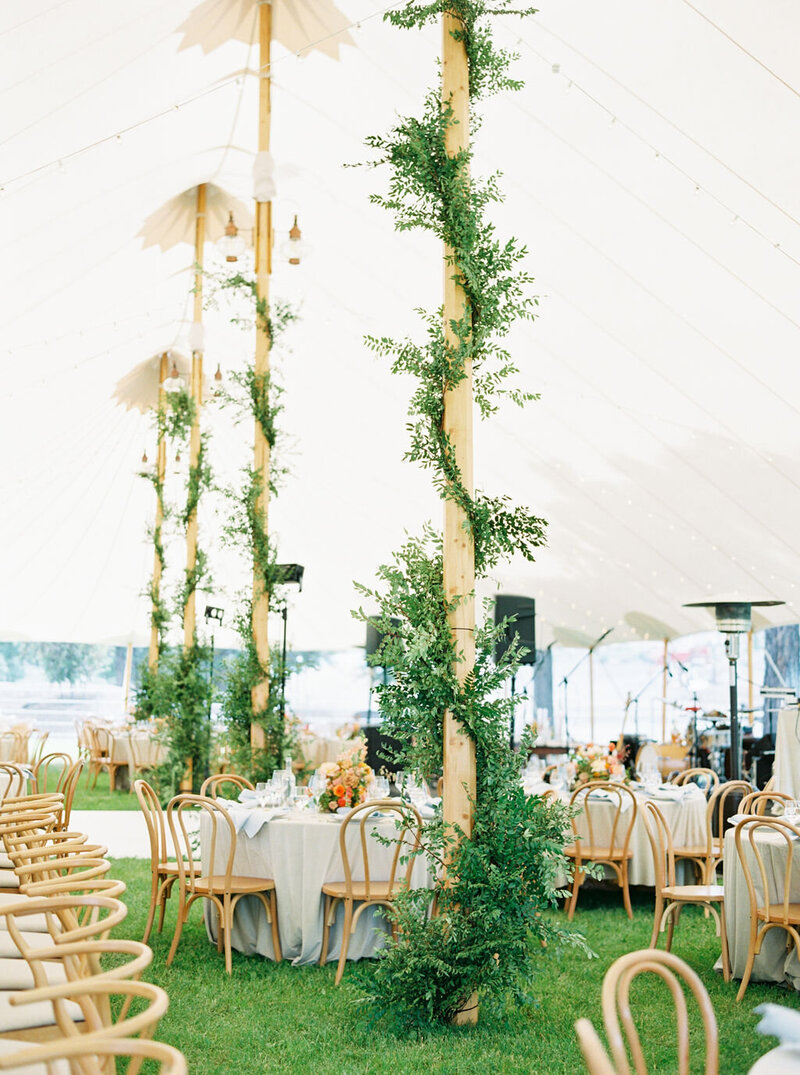 Sperry sailcloth tent reception with greenery-wrapped tent poles and natural light filtering through canvas, designed by Summer Robbins Flowers in Bend, Oregon