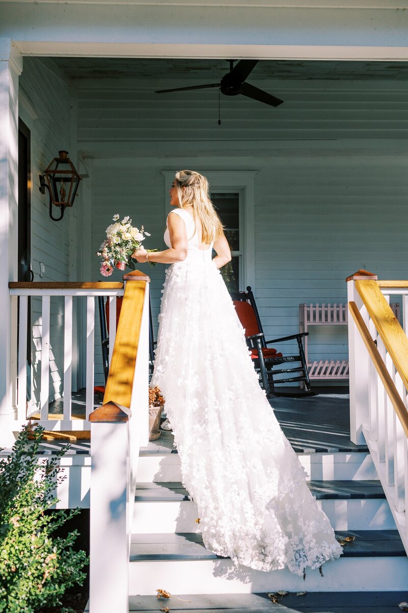 Bride with long train walking up stairs of Craftsman style house
