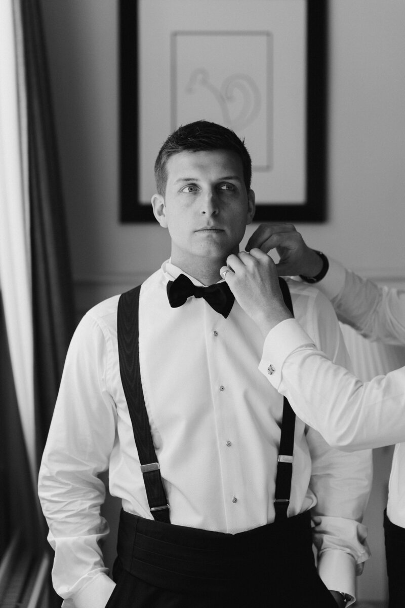 Usher putting on the grooms bowtie at Lower Slaughter Manor House by Cotswold wedding photographer Adorlee weddings