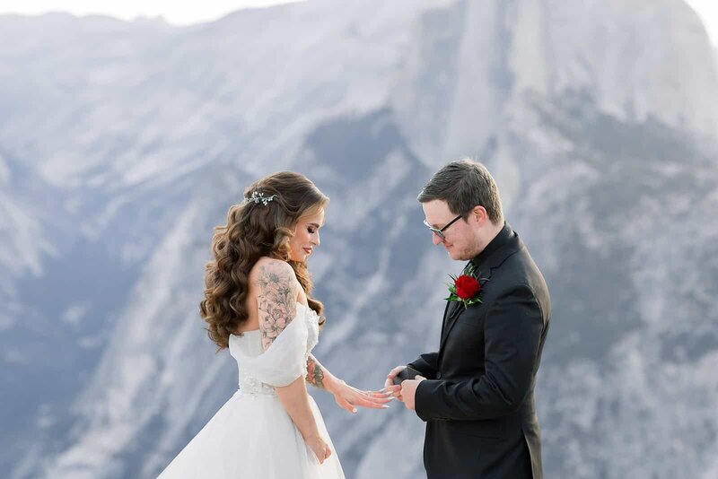 A groom slips a ring on a brides finger at Glacier Point in Yosemite National Park. 