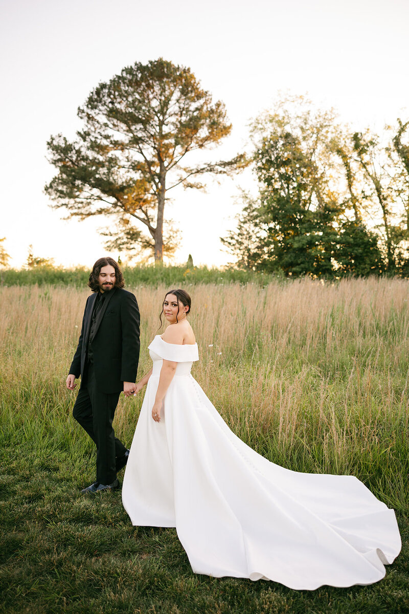 Bride and groom walking through grassy field at vibrant Tennessee wedding