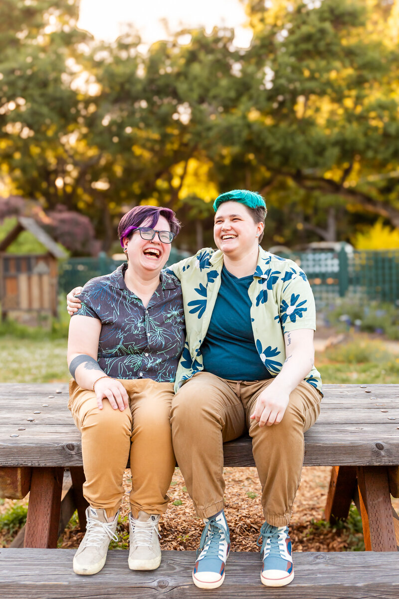 nonbinary trans couple engagement photography sitting on picnic table in a garden