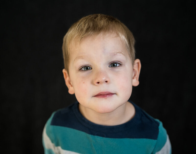 A young boy looks pensively into the camera during his fine art school portrait session in Minneapolis, MN.