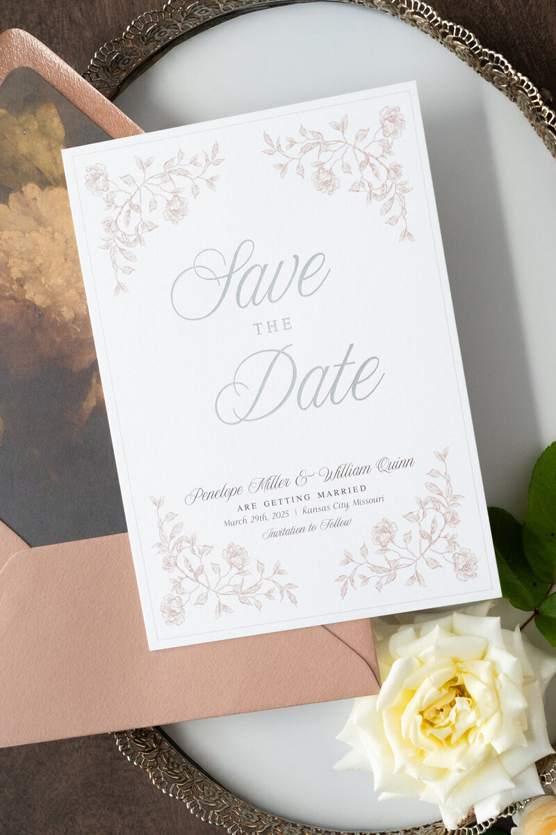 White curved menu card on a plate with a brown velvet napkin and flowers