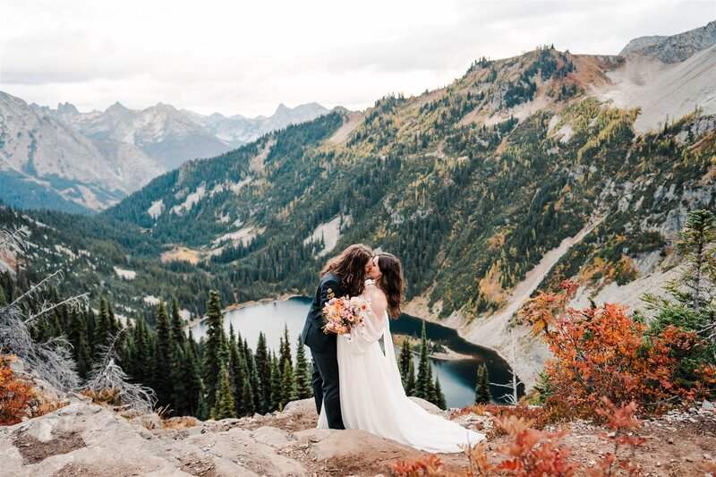 Bride & grooms kissing above lake on Maple Pass Loop during their adventure elopement in the North Cascades!