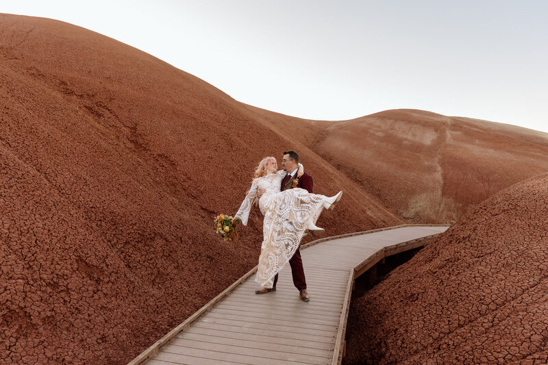 Bride and groom sitting on a bench in the Akron Art Museum with a gallery of paintings behind them. 
