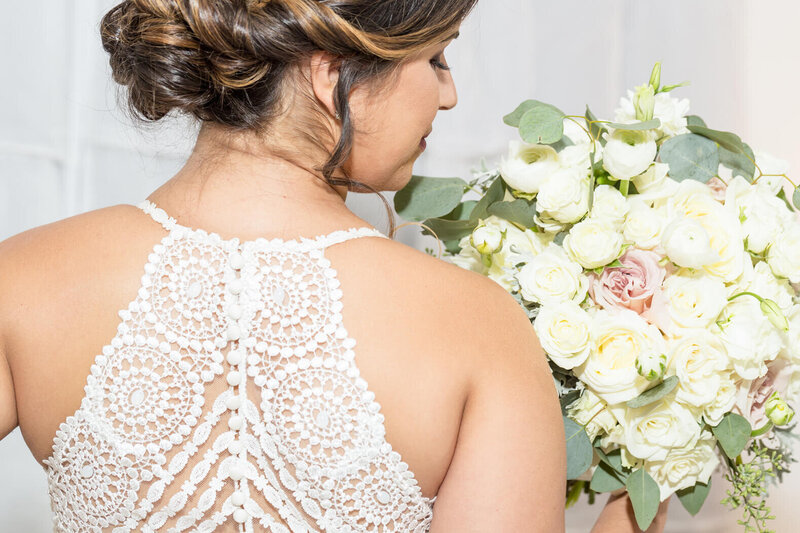 Bride looking over her shoulder while holding a white rose bouquet, photographed during her wedding day photo timeline by Miami wedding photographer.