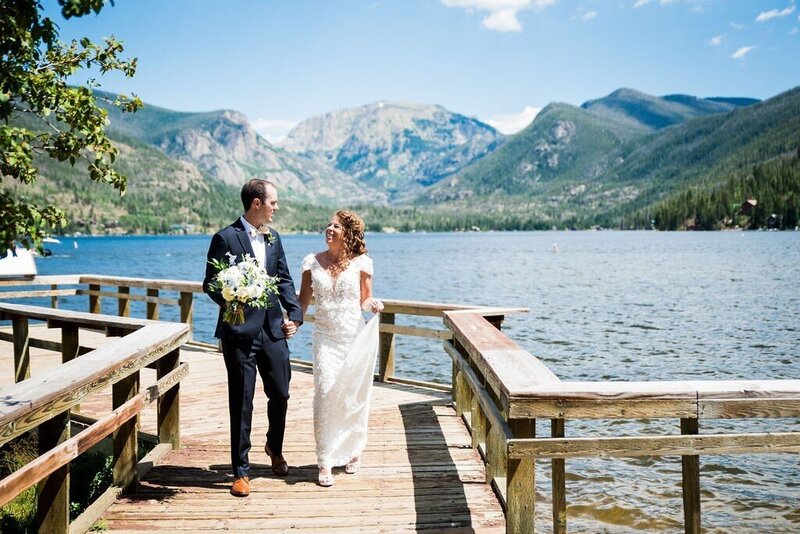 wedding couple holding hands on dock over water in CO