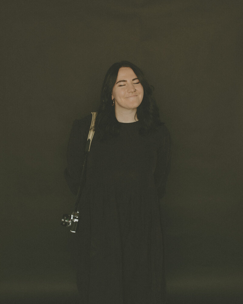 girl smiling with a film camera hanging on her shoulder