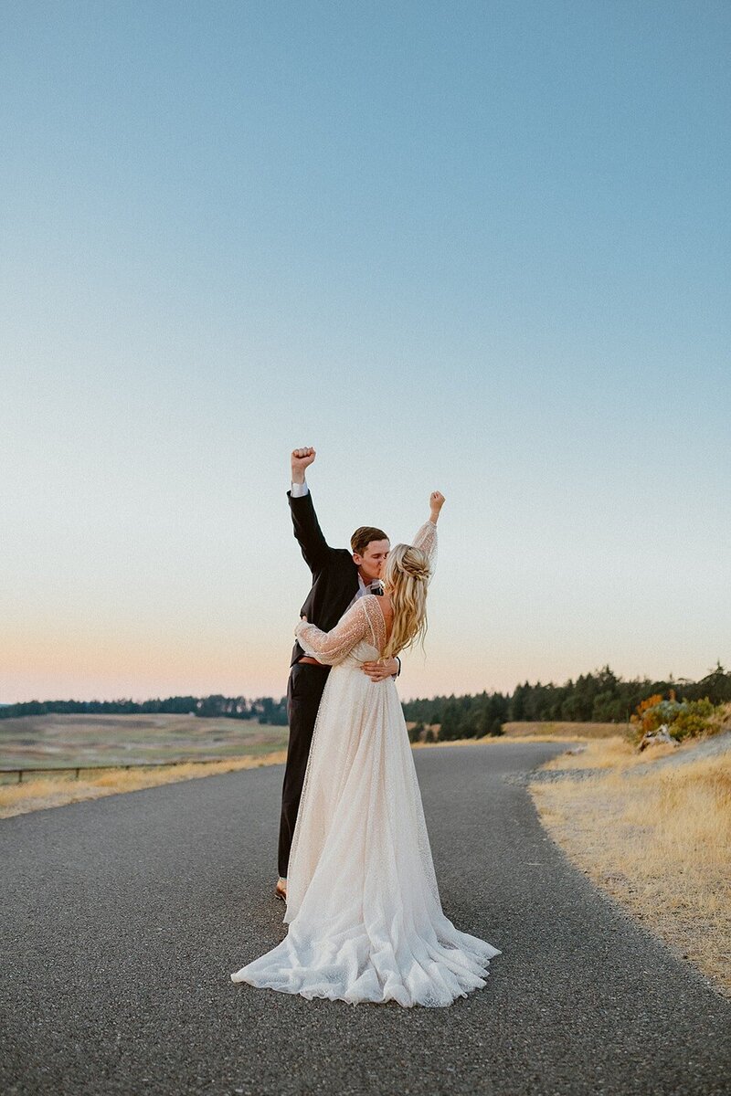 Couple Kissing While  Celebrating with Fists in the Air - Jessica & Chris | Golf Course Wedding Seattle Washington