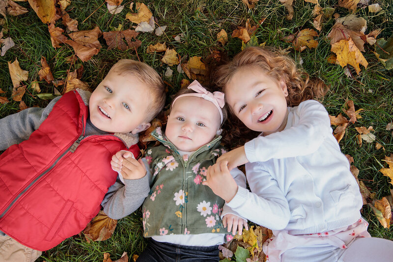 Big brother helps little brother stand up in field of yellow flowers at family photoshoot