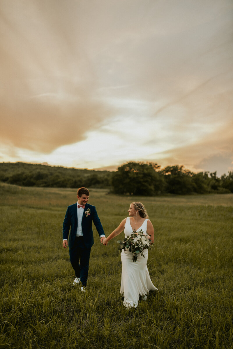 bride and  groom waling in a grassy field