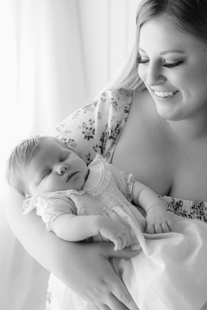 Beautiful black and white image of a young mom holding her baby girl wearing a pink heirloom dress in Savannah, GA