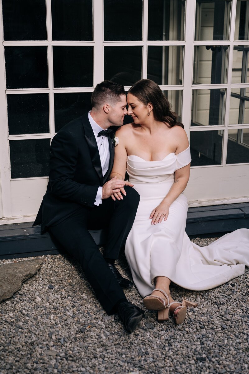 a bride and groom sit in front of cream panel door at the winehouse wedding venue in gibbston valley