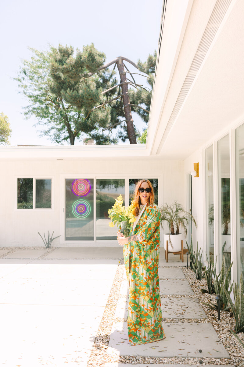 Outdoor branding session featuring a woman in a green retro robe with yellow florals and colorful neon art in the background. Greenville SC. Dani Lacey Photographs.