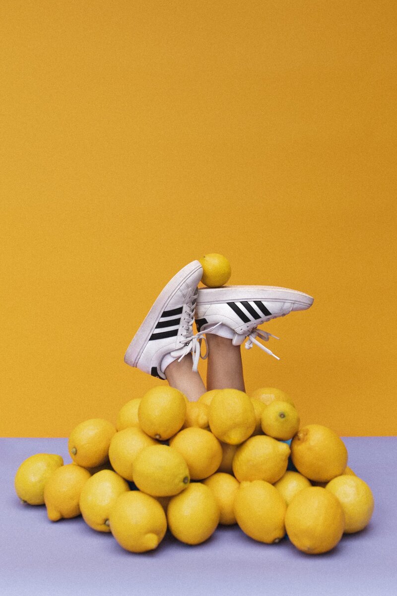 Pile of lemons with feet poking out of the top balancing one lemon.