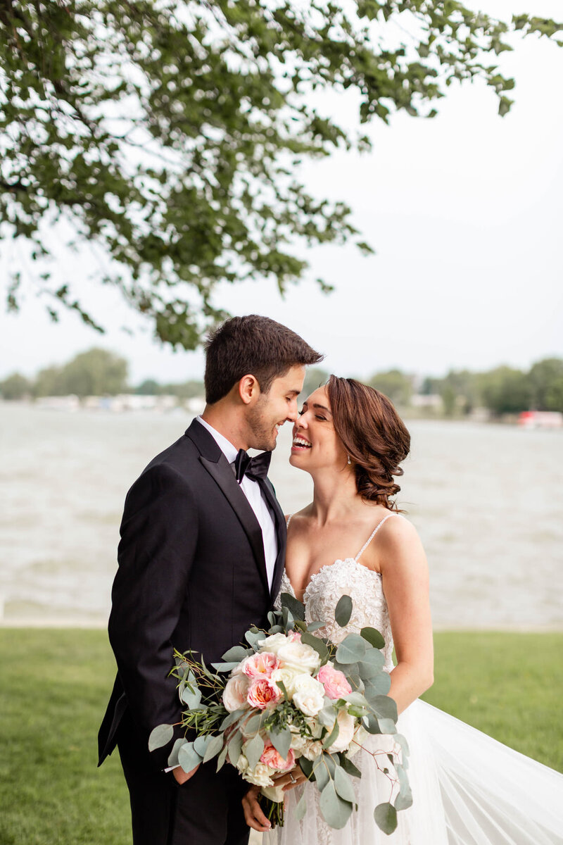 Bride in spaghetti strap white gown with clean makeup and a low soft updo, touches noses with her groom, Indianapolis Bridal Hair and Makeup
