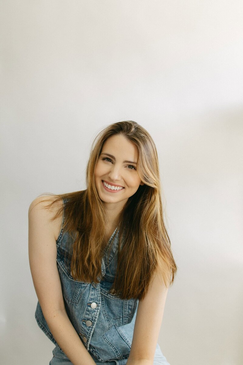 A woman sits smiling at the camera.