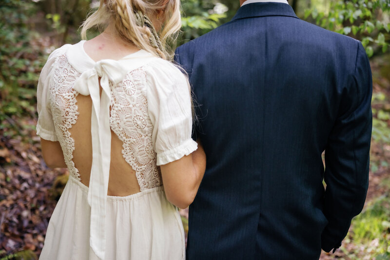 bride holding the grooms arm as they walk down a path in the woods in the Smoky mountains