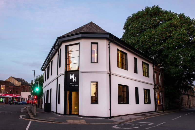 Two-story black and white corner building photographed at dusk with glowing windows, shown for Montgomery House case study