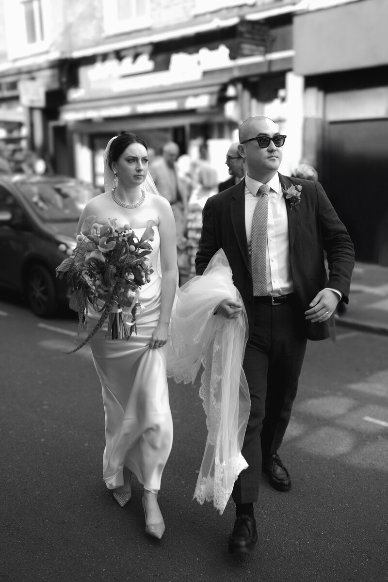 Jessica and Francis walk the streets of central London after their wedding ceremony at The old Marylebone town hall in central London