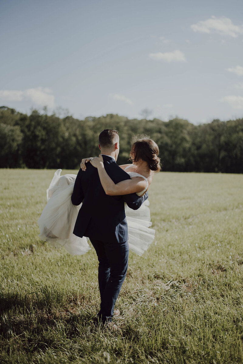 couple de jeunes mariés traversant un champ