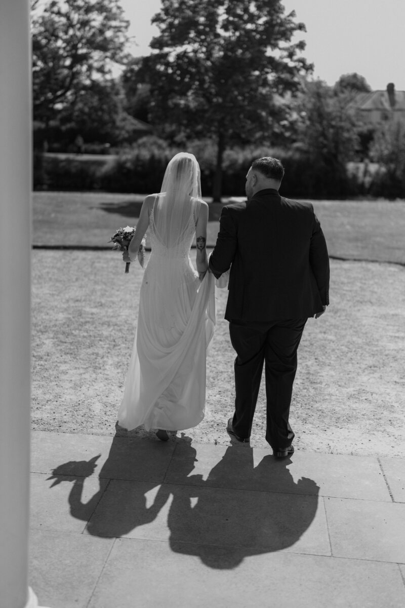 Wedding photographer captures couple taking a stroll hand in hand at their french chateau wedding.