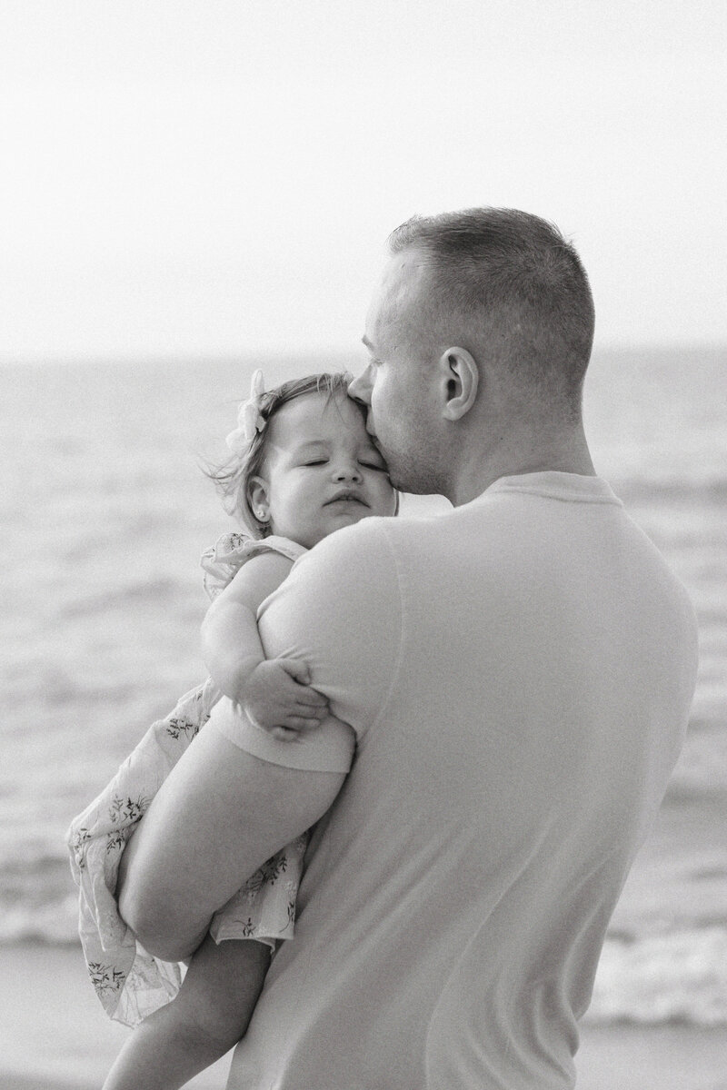 father kissing his baby black and white