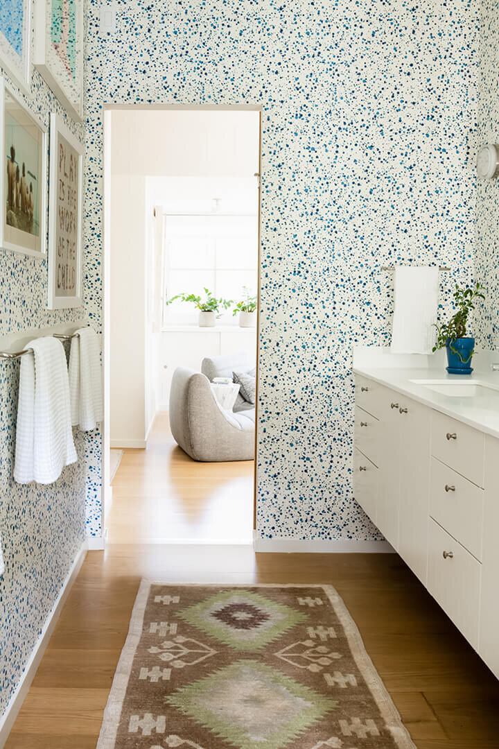 Boston interior decorator designs a Hingham new construction bathroom with Hinson splatter wallpaper, a modern vanity, and a vintage area rug.
