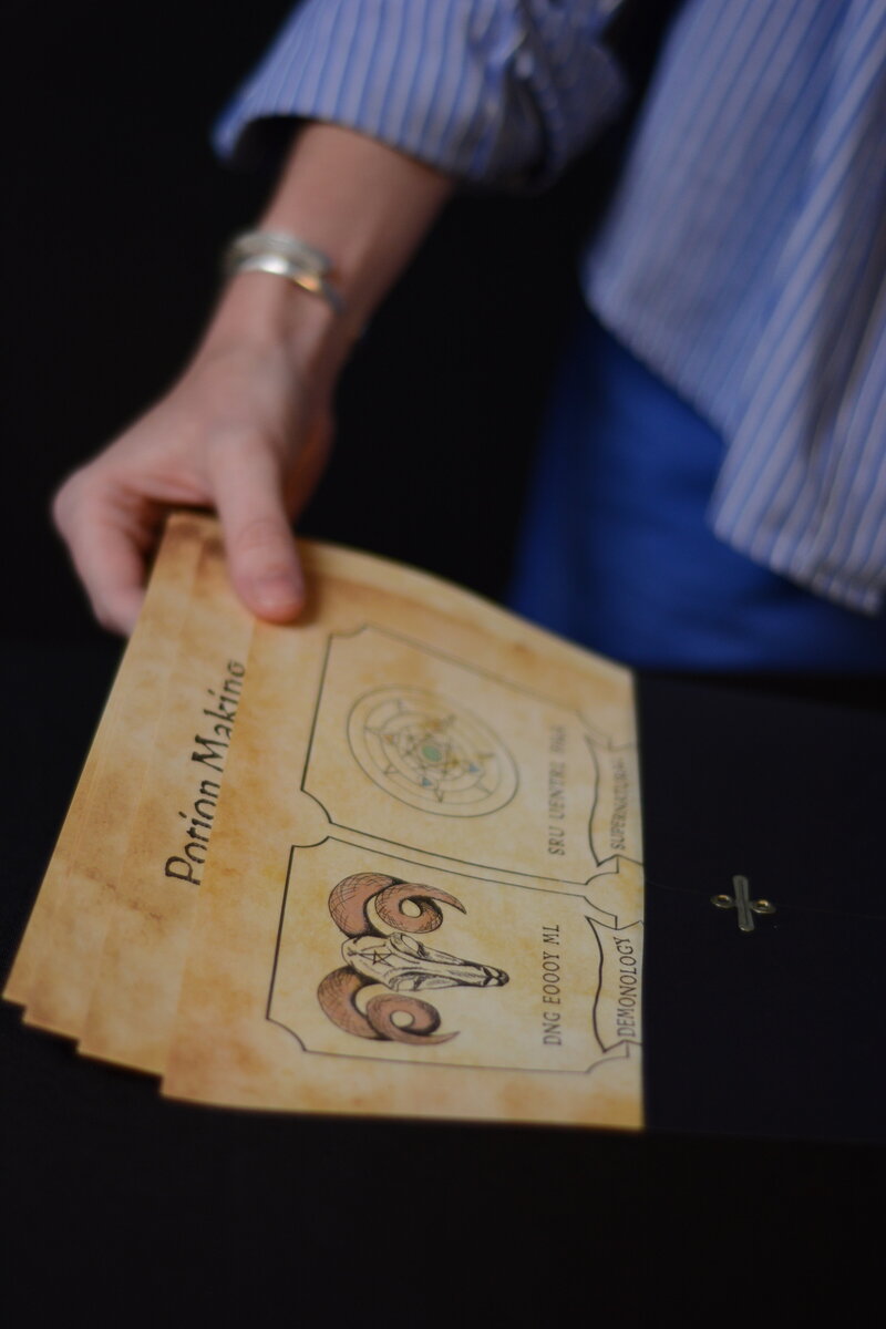 A hand pulling out puzzle pages from a black envelop