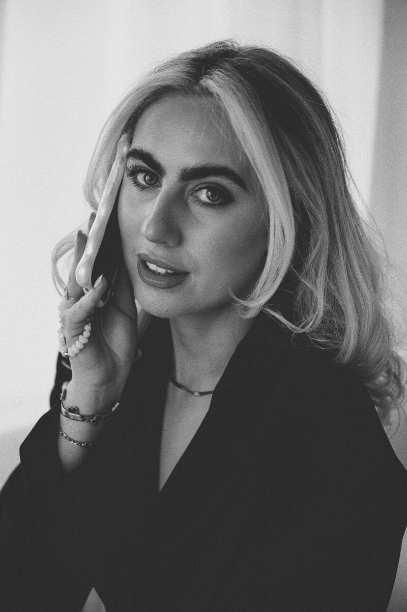 Black and white close-up portrait of Amelia Waters holding a phone, founder of Sunday Social Collective