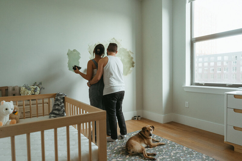 man and woman painting nursery during NYC maternity photos by Elsie Goodman Photography