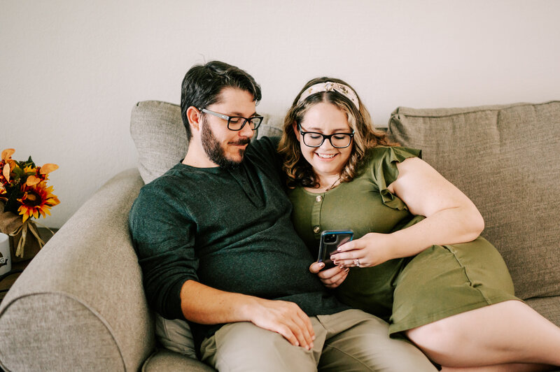 couple sitting on a couch looking at blogs on a phone
