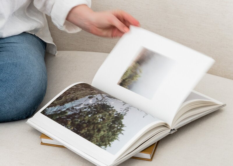 Woman sitting on a couch flipping through a book of photographs