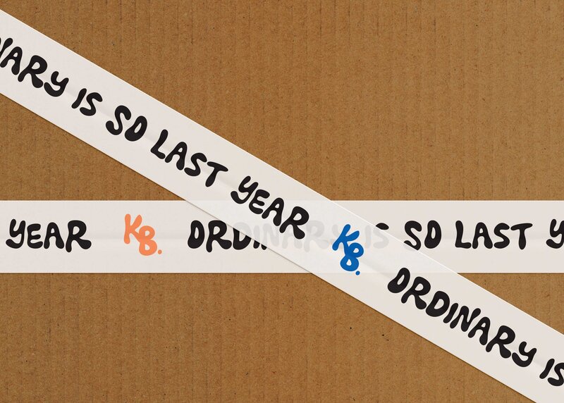 Packing tape with colorful photography branding and the words 'ordinary was so last year' written on it.