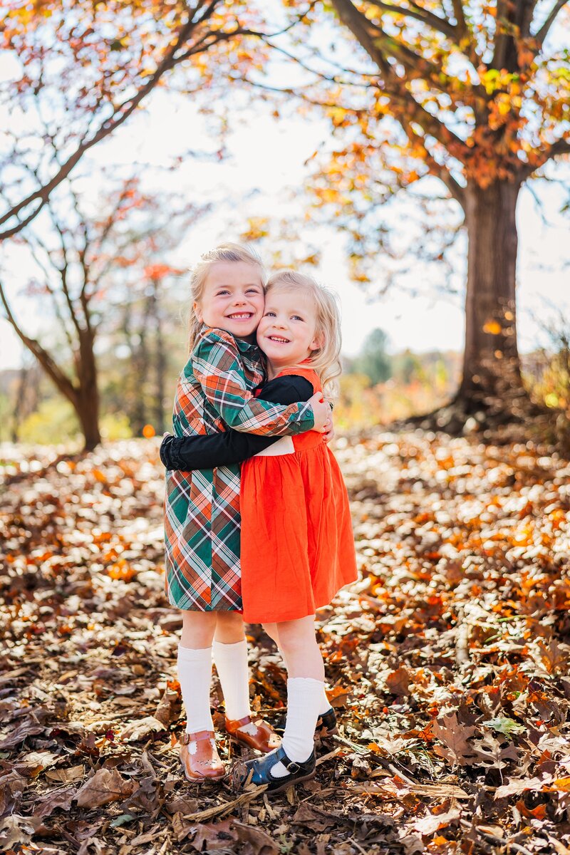 Little girls hugging in the fall at a mini session with Melissa Sheridan, Northern Virginia Photographer