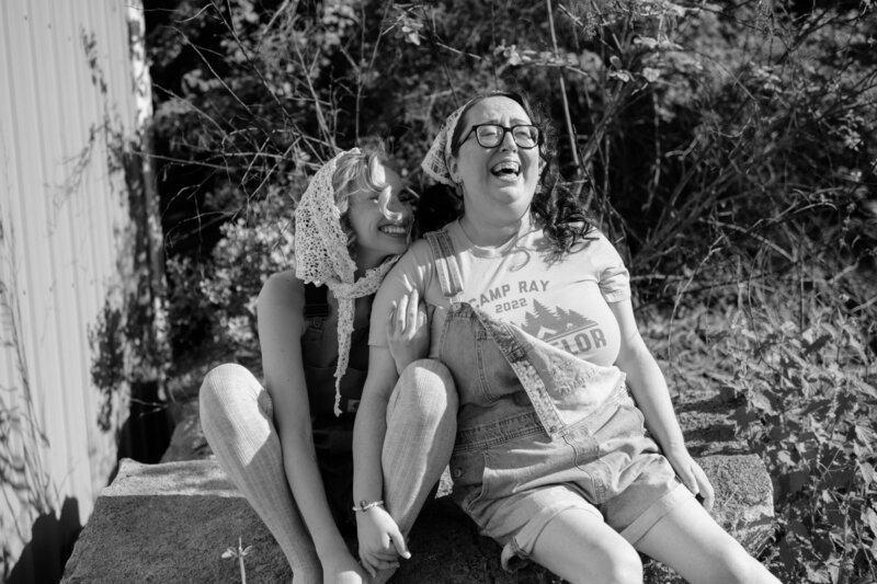 portrait of seattle wedding photographers laughing together in vintage-inspired outfits, highlighting authentic connection and joy