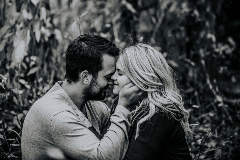 black and white  photo of couple  with man holding her face with eyes closed