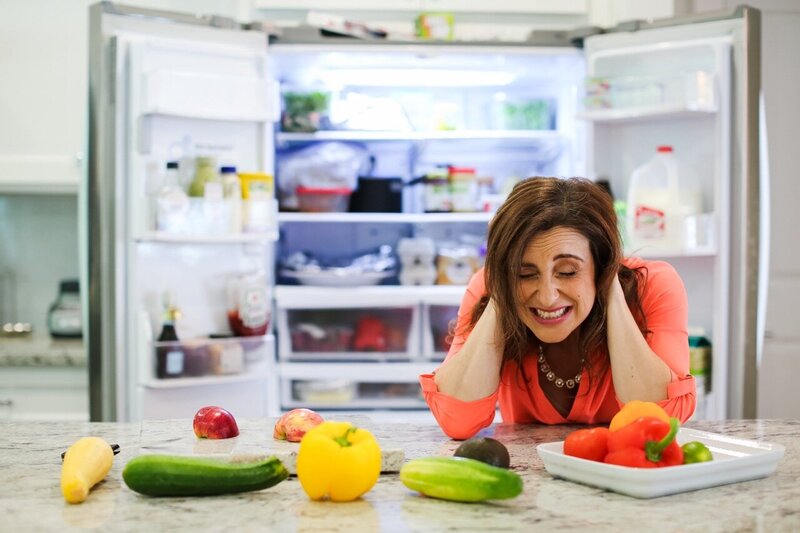 Vanessa looking overwhelmed in front of an open fridge, surrounded by healthy foods