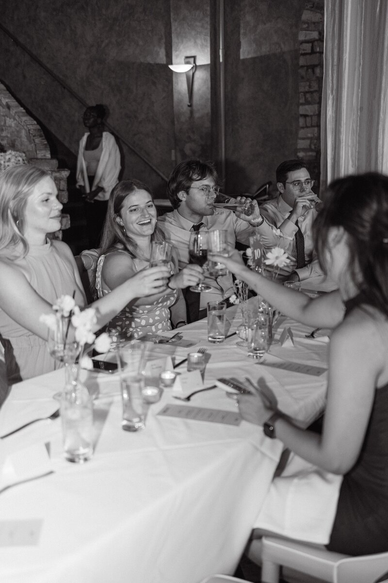 Wedding guests raising glasses for a toast during a candid Colorado wedding reception at a european-inspired venue.
