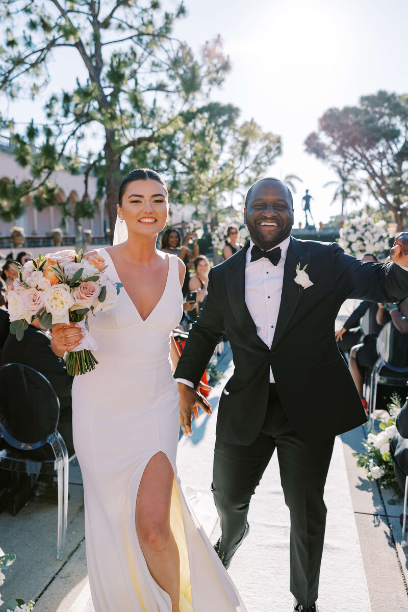 Bride and Groom walking down the aisle holding hands at The Ringling Museum