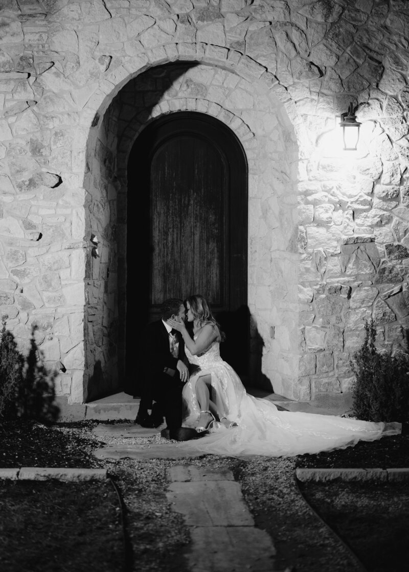 wedding couple sitting on doorstep kissing