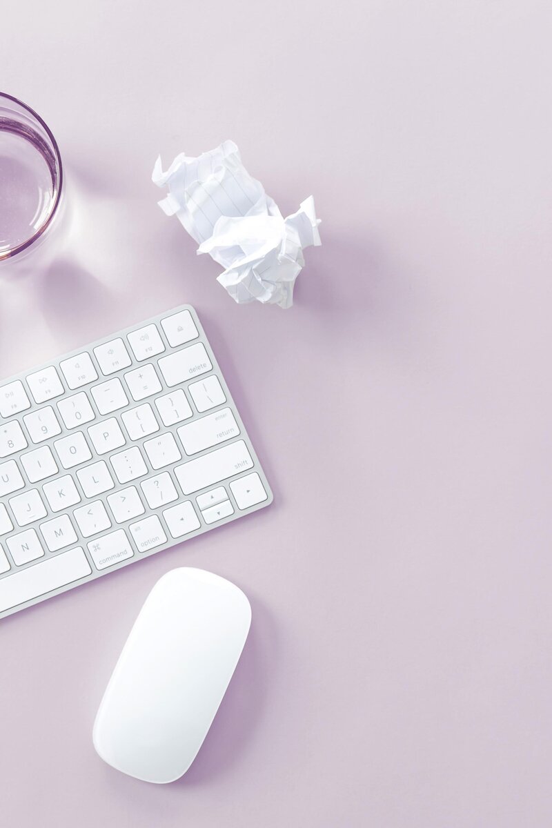 Teclado y papel arrugado sobre  fondo lilac.