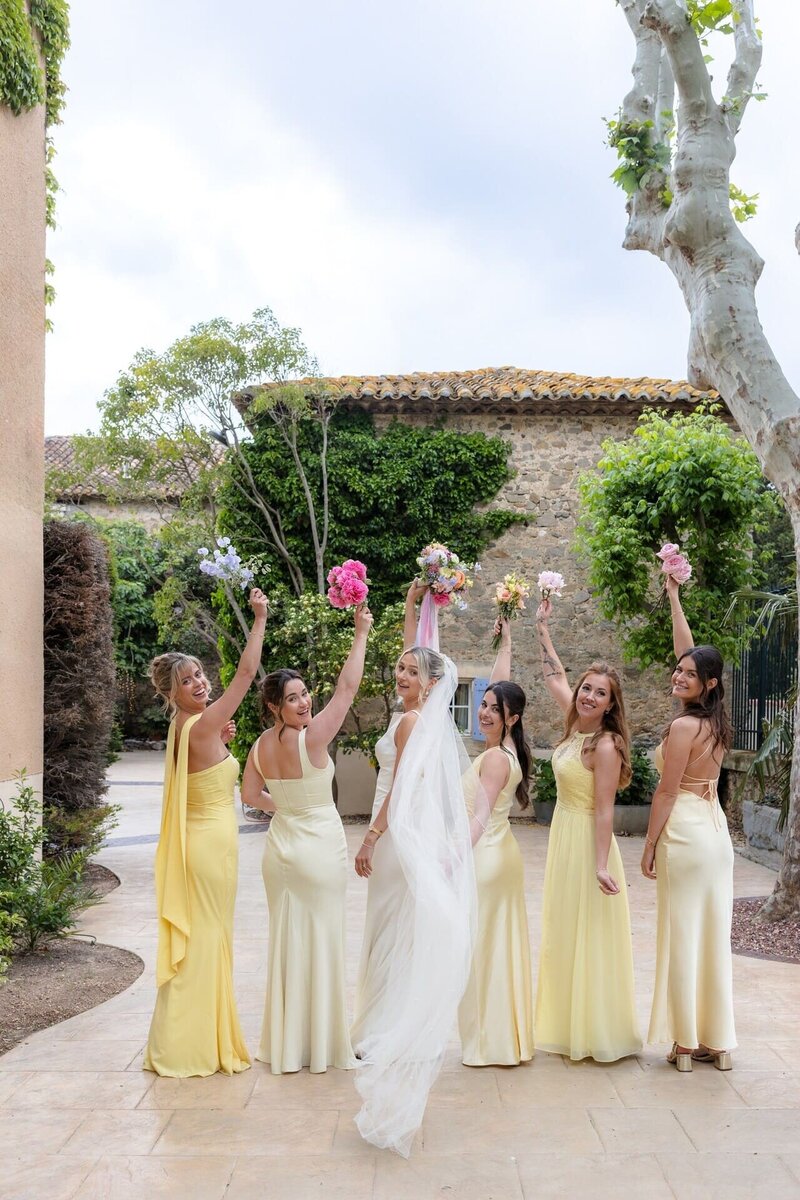 joyful-bride-and-bridesmaids-raising-bouquets