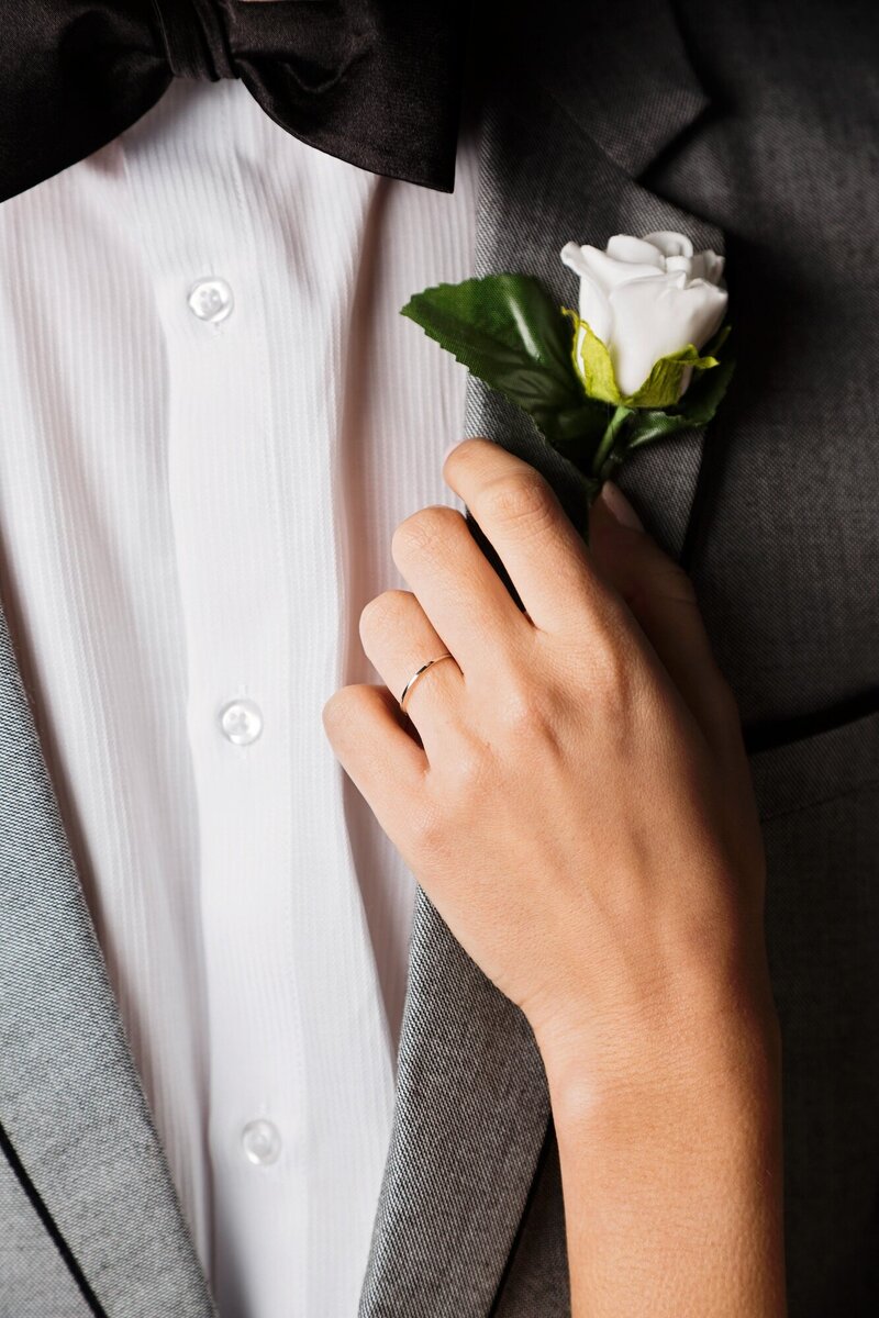 Bride attaching boutonniere to grooms suite